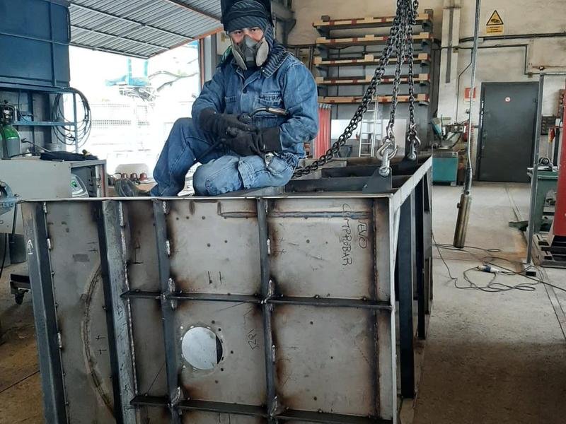 Soldador trabajando sobre un cajón de chapa de acero reforzado en el taller